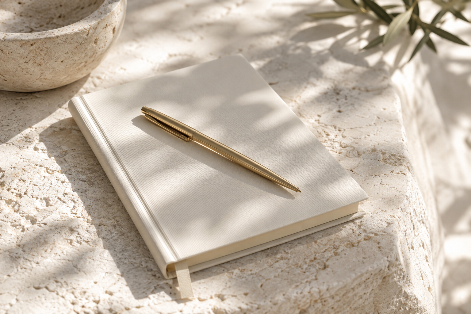 Cream notebook and gold pen in soft daylight